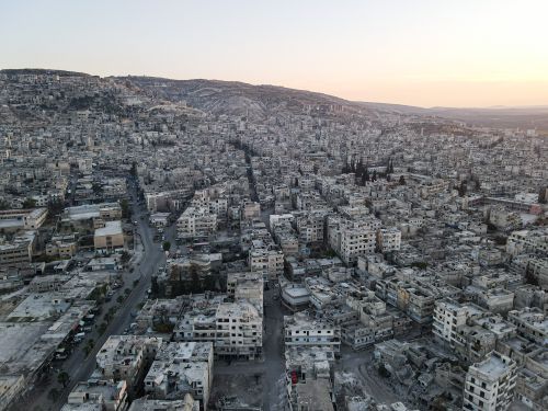 Free Drone shot of Idlib cityscape at sunset, showcasing dense urban layout and historic architecture. Stock Photo