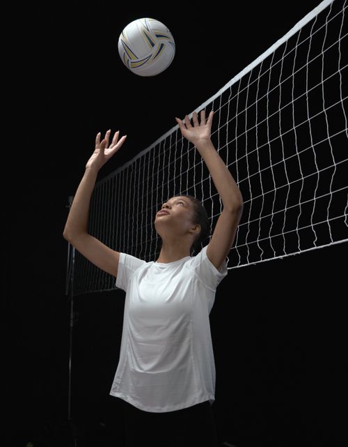 Free A focused female athlete playing volleyball in a studio setting, preparing for a serve. Stock Photo