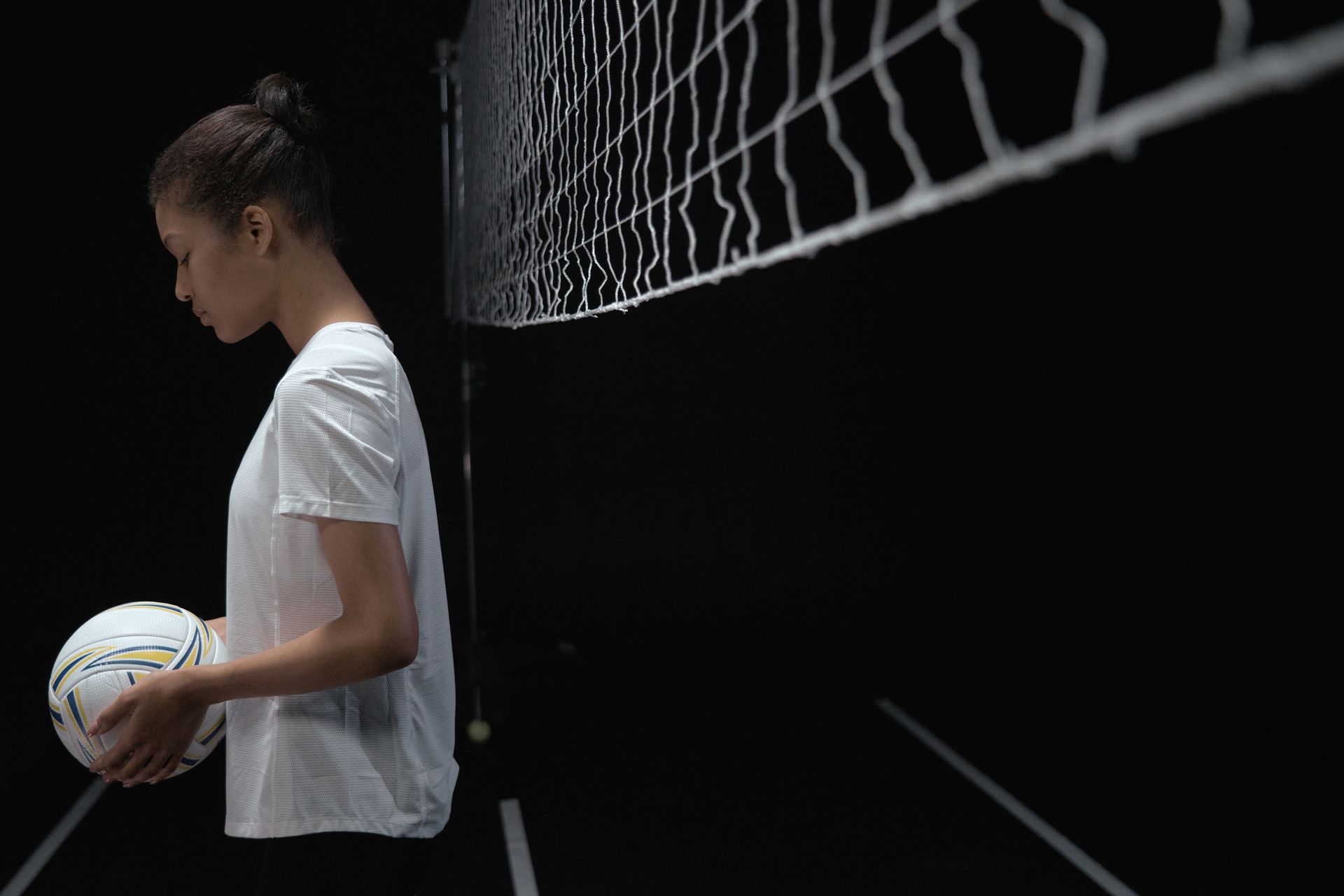 Focused female volleyball player holding a ball in a studio setting.