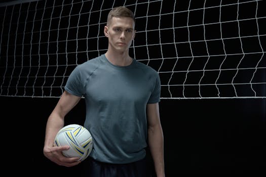 Male volleyball player holding a ball in a studio setting, ready for action.