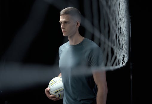 Profile image of a male volleyball player holding a ball in a studio setting with a net.