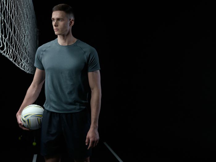 Player holding a volleyball beside a net in a studio
