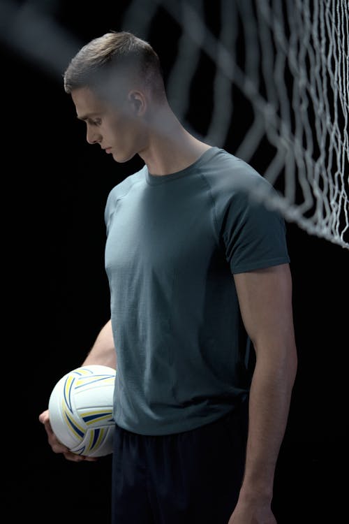 Man Holding a Ball While Looking Down