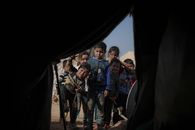 A group of children peering into a tent in a refugee camp in Syria, capturing their curiosity and hope.