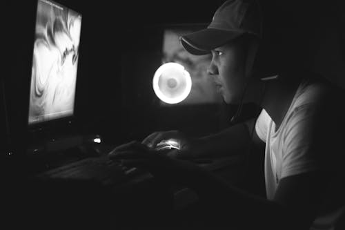 Man in White Shirt Wearing Black Cap and Headphones