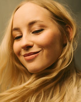 Close-up portrait of a smiling blonde woman with natural lighting and soft tones.