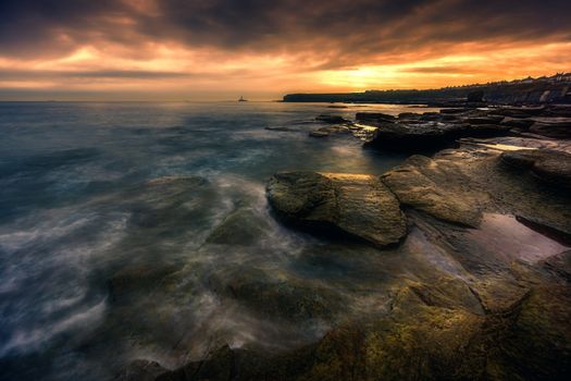 Captivating sunset view over a rocky coastline with dramatic skies and ocean waves.