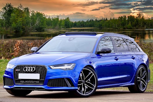 A modern blue Audi RS6 parked by a lake with scenic forest and sky backdrop.