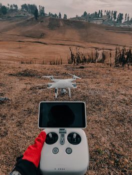 Aerial view of Gulmarg with drone controller and landscape in focus.
