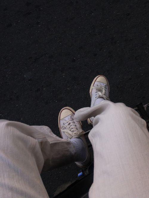 Free White sneakers with white pants over dark pavement, urban style aesthetic. Stock Photo