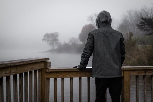 Back View of Person in Black Hoodie Looking at the Foggy River