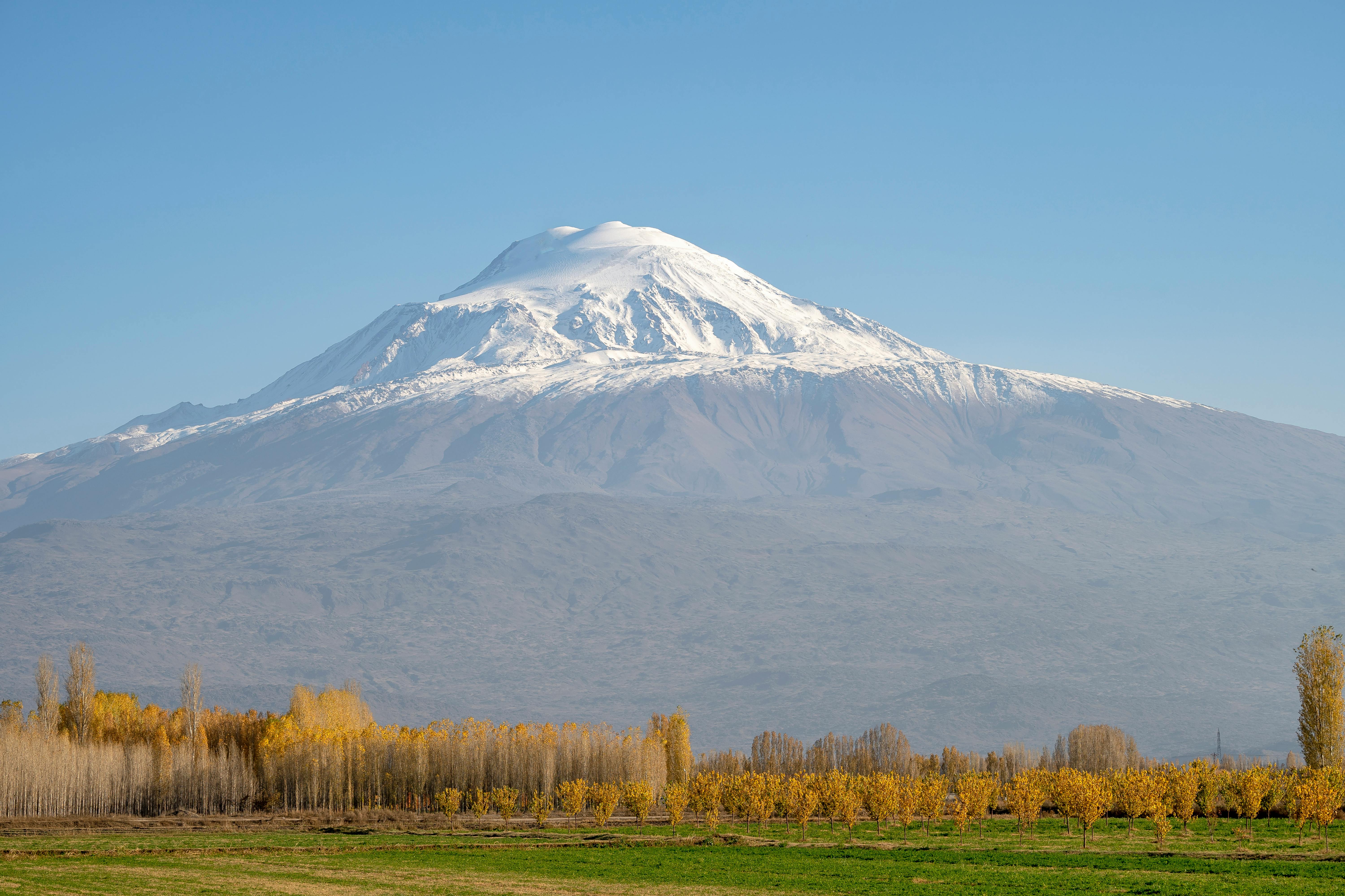 A stunning view of snow-capped Mount Ararat in Turkey surrounded by autumn foliage and clear skies.