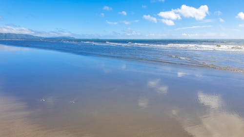 Gratis stockfoto met blauwe lucht, kleine golven, nat zand