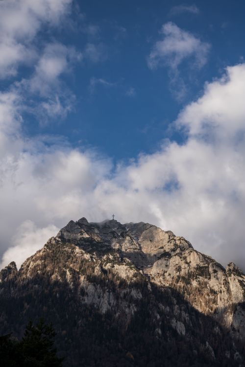 Free Dramatic mountain peak with rocky textures under a vast blue sky and clouds. Stock Photo