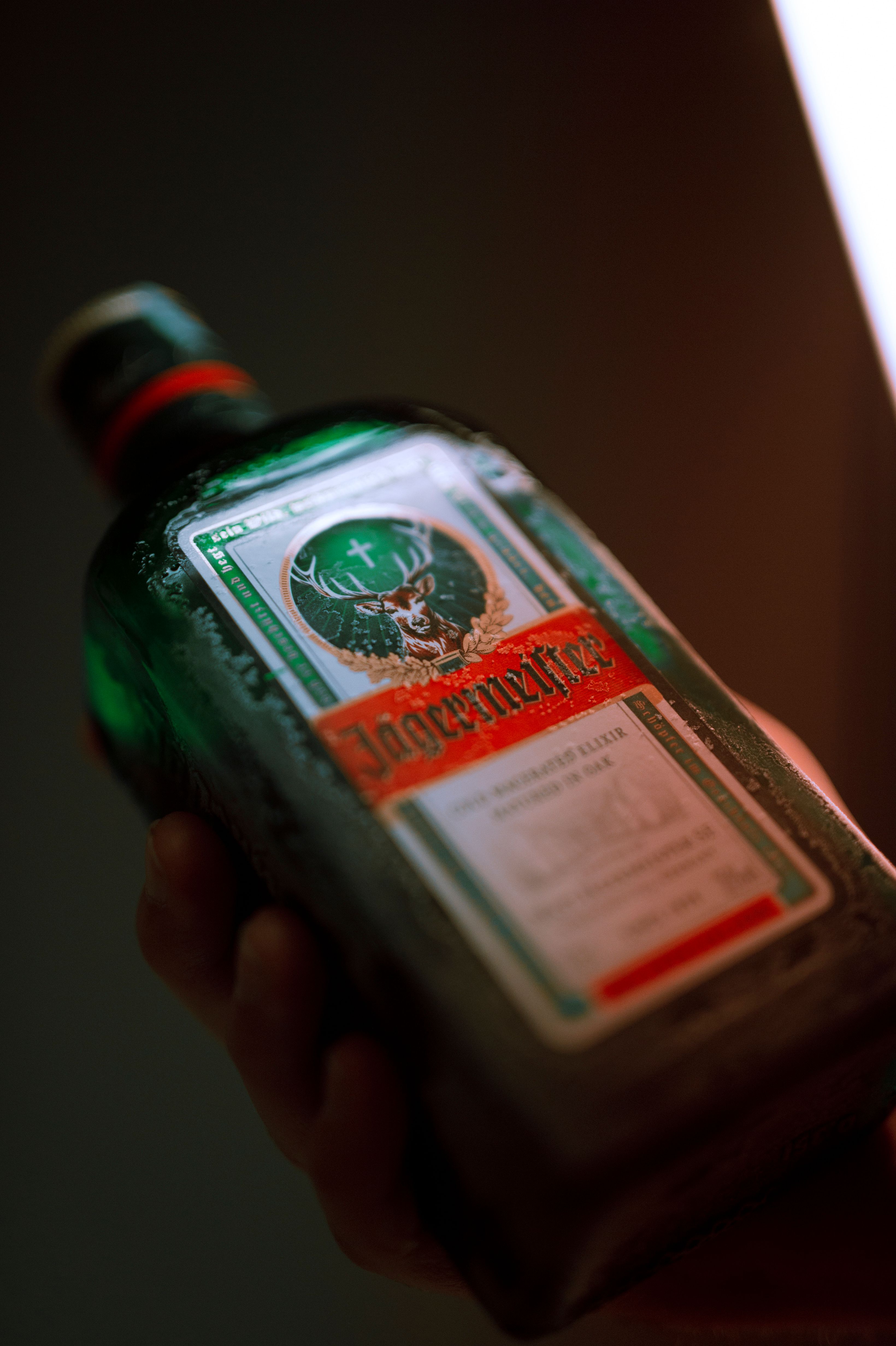 Detailed shot of a Jägermeister bottle being held, showcasing brand label and design.