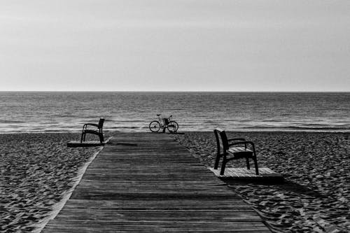 бесплатная Фотография велосипеда на берегу моря в оттенках серого Стоковое фото
