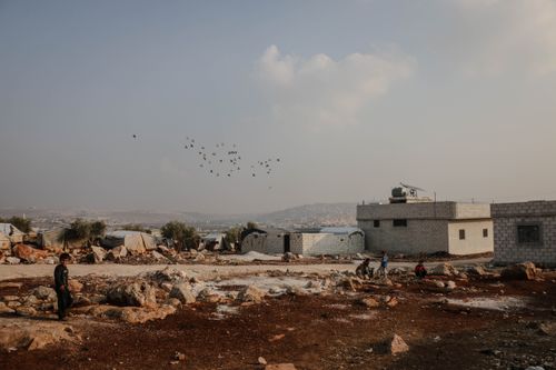 Free Scenic view of a village in Idlib, Syria, with people amidst arid landscape and scattered buildings. Stock Photo