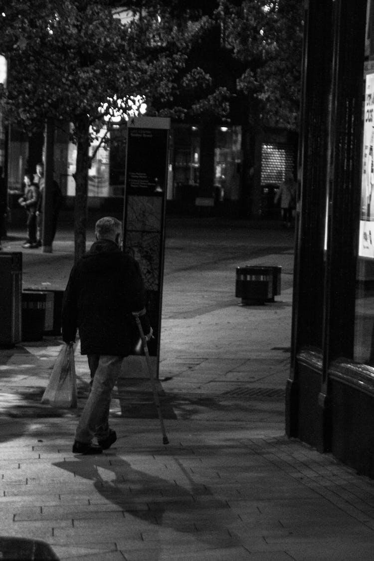 A Man In Black Jacket Walking On Sidewalk 