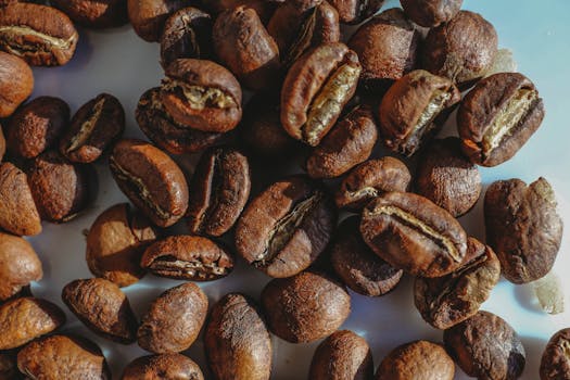 Detailed close-up image of aromatic roasted coffee beans on a flat surface.