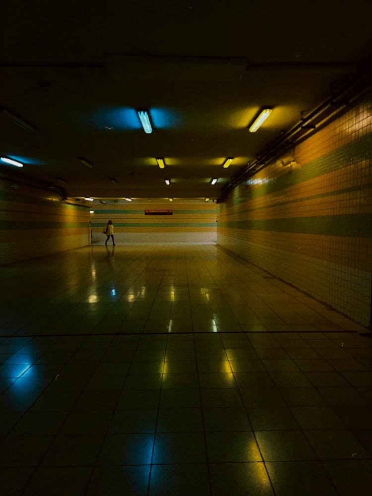 A Person Walking On Hallway With Lights Turned On During Night Time