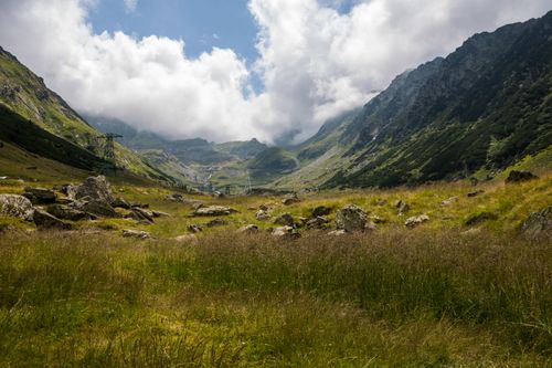 Free A picturesque mountain valley with lush greenery and dramatic cloud formations. Stock Photo