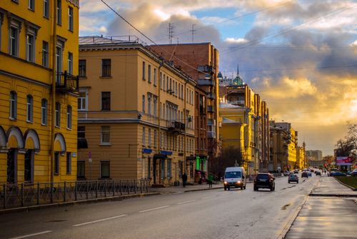 Free A bustling urban street with classic architecture during sunset, featuring vibrant sky and vehicles. Stock Photo