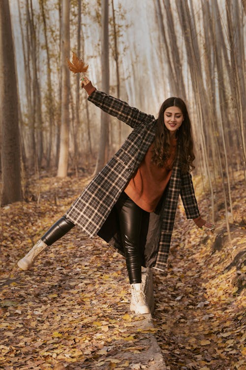Woman in Black and Brown Plaid Coat Standing on Brown Dried Leaves