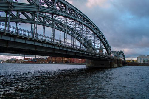 Free Dramatic view of a suspension bridge spanning across a river with urban architecture. Stock Photo