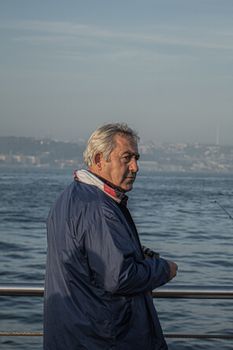 Senior man enjoys fishing by the sea at sunrise, capturing serenity and leisure.