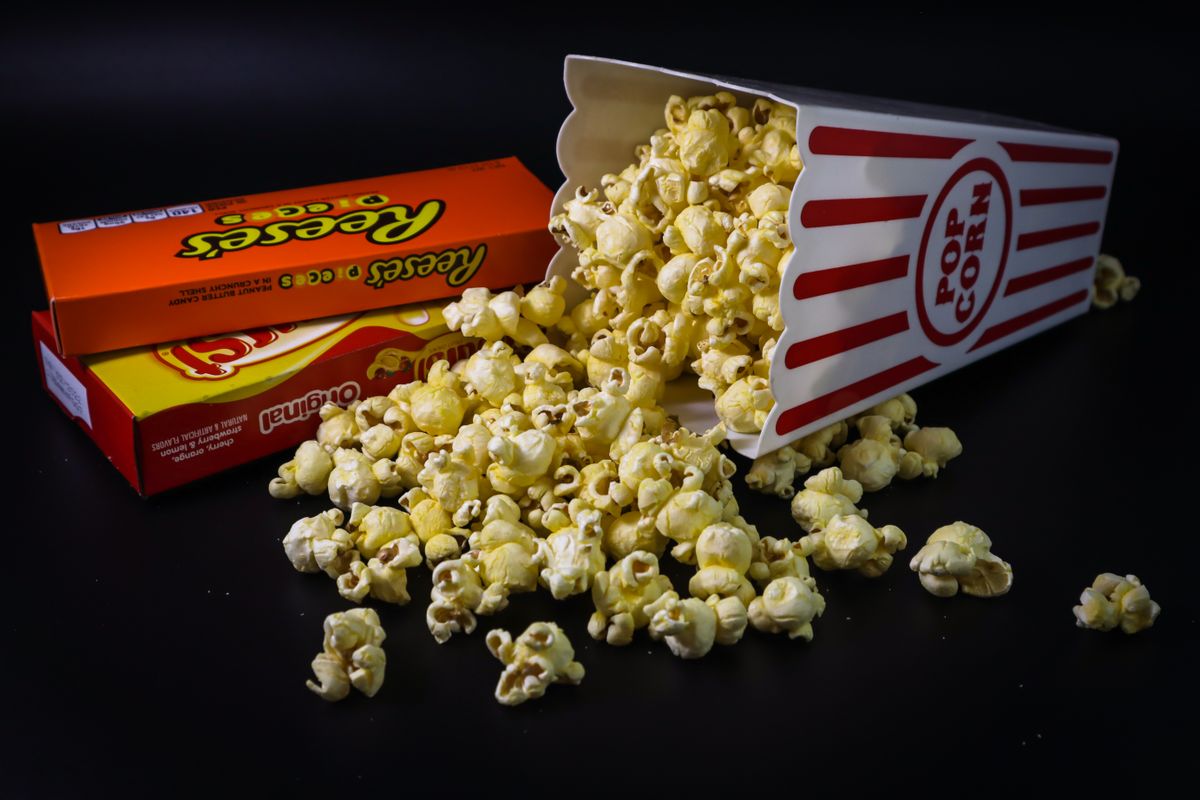 Close-up of popcorn and candy boxes spilled from a classic striped box. Perfect for snack-themed imagery.
