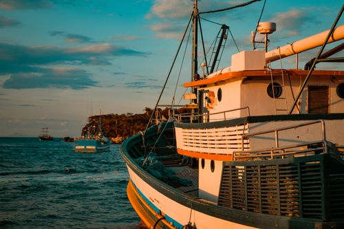 Free Fishing boats gently sway at sunset on a serene sea, showcasing nautical tranquility and vibrant evening hues. Stock Photo