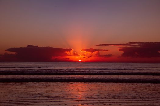 Beautiful sunrise over the ocean with vibrant colors and serene beach setting.