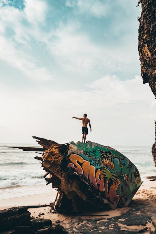 Free Photography of Man Standing on Destroyed Part of Ship Stock Photo