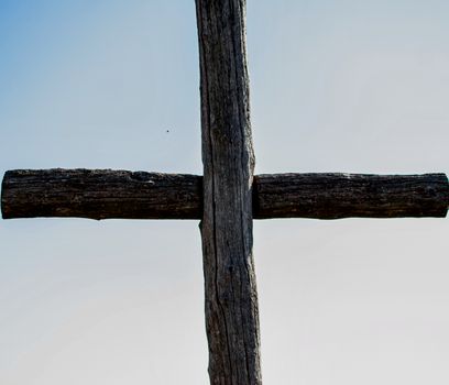Wooden cross against a clear blue sky, symbolizing Christianity and spirituality.