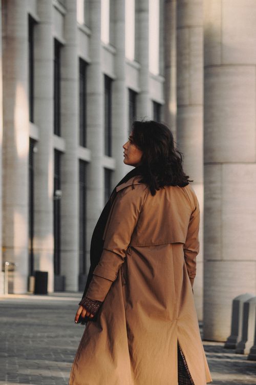 Free A fashionable woman walks past modern architecture in an urban setting. Stock Photo
