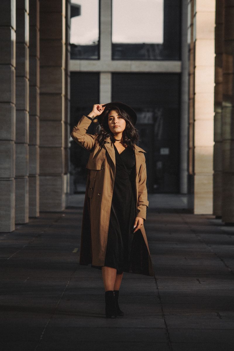 woman in belted trench coat over black slip dress