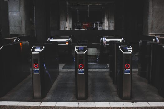 Photo by Czapp Árpád A row of modern turnstiles at an underground subway entrance at night.