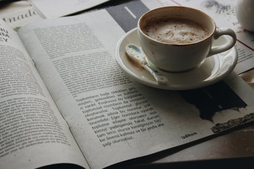 Free Cup of Coffee on a Saucer on Top of a Book Stock Photo