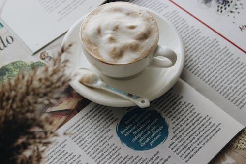 Free White Ceramic Cup and Saucer on Newspaper  Stock Photo