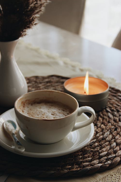 Free Cup of Coffee and Lit Tealight Candle Stock Photo