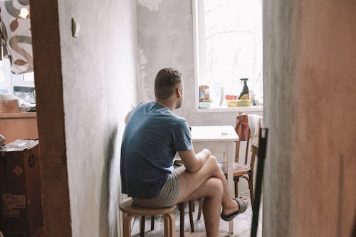 Man in Blue Shirt Sitting on Brown Wooden Chair