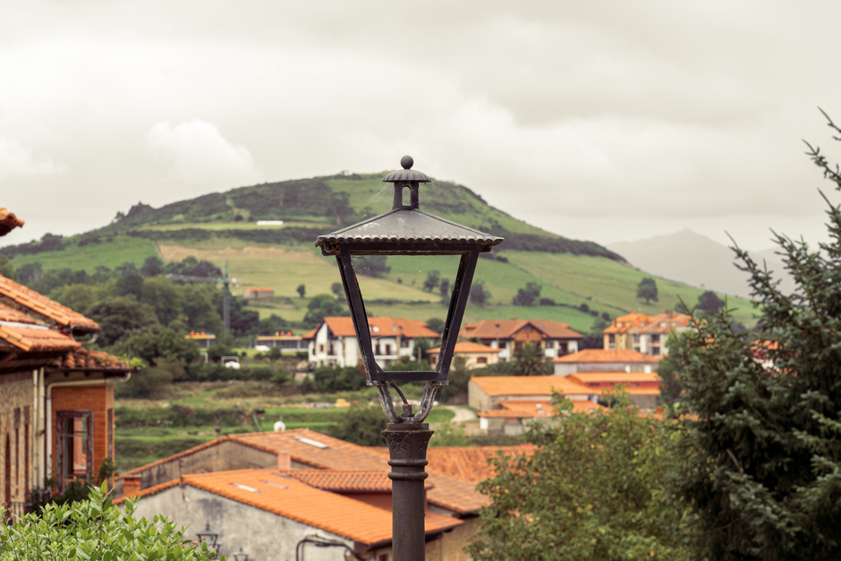 Vista escénica de un pintoresco pueblo español con colinas y una linterna vintage.