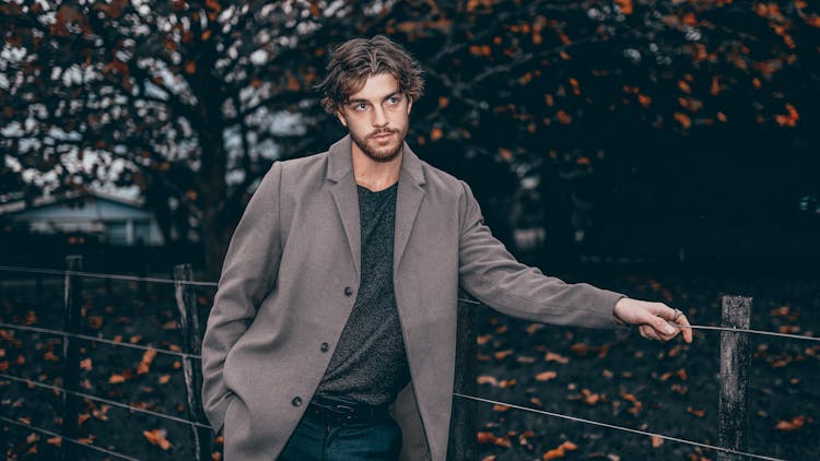 Man In Coat Posing By Fence