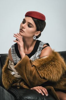 Stylish woman posing indoors with a red beret and fur coat, exuding elegance.