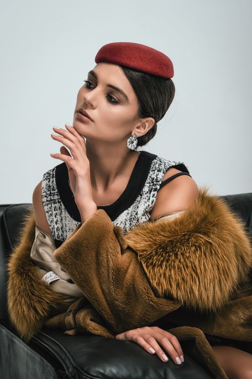 Free Stylish woman posing indoors with a red beret and fur coat, exuding elegance. Stock Photo