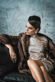 Sophisticated woman in a sequin dress and fur coat, exuding luxury and elegance.