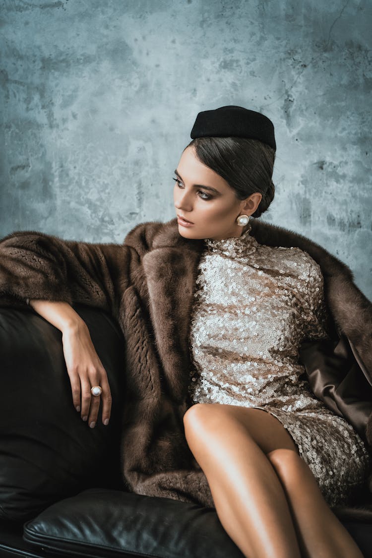 Woman Sitting On A Leather Sofa In A Fur Coat