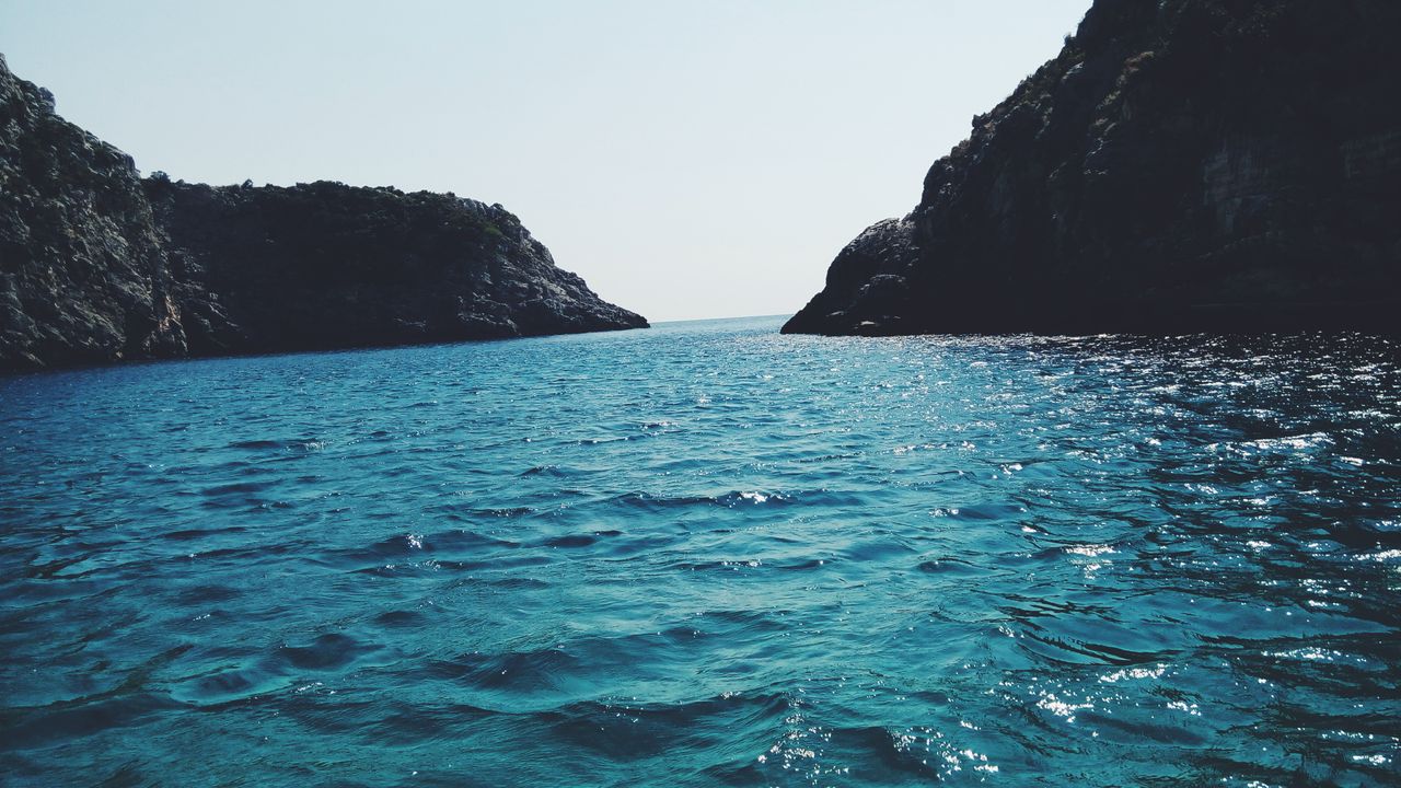 breathtaking view of a serene ocean with distant rocky cliffs under a