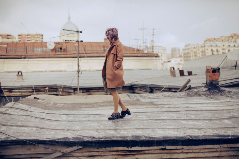 Woman in coat poses on rooftop in Agjabadi, Azerbaijan.
