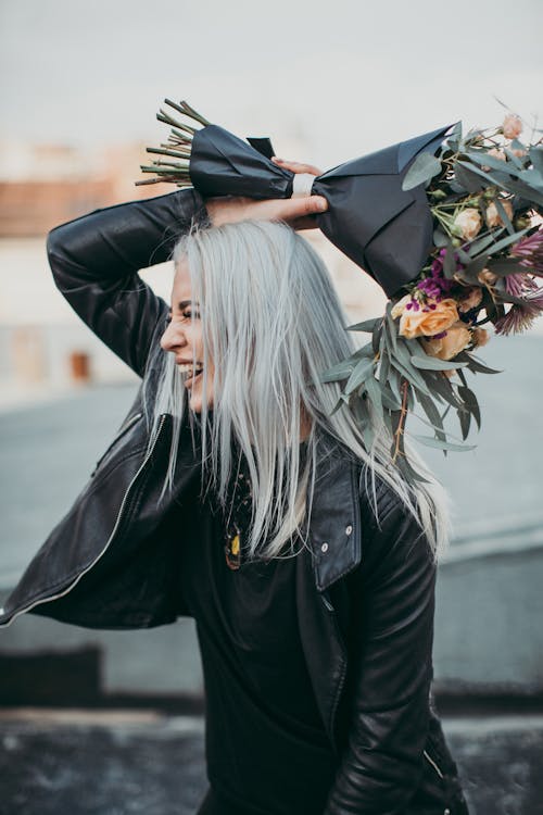 Женщина в черной кожаной куртке, держа букет цветов